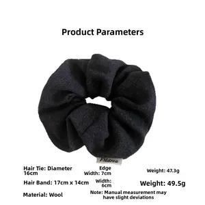 Detail of black wool fabric scrunchie with soft knitted texture and brand tag