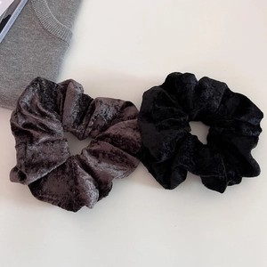 Close-up of black and dark grey velvet hair scrunchies with soft snowflake fleece texture