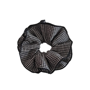 Elastico scrunchie classico a quadretti bianchi e neri con pieghe su sfondo bianco