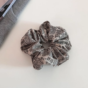 Close-up of beige paisley scrunchie with vintage floral pattern and soft silk texture