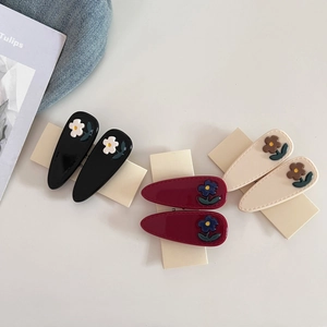 Close-up of acetic acid flower hair clips in black, burgundy and cream colors set
