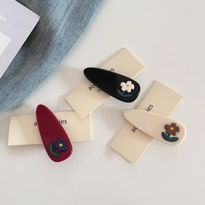 Close-up of acetic acid flower hair clips in black, wine red, and cream white colors