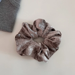 Detail shot of champagne velvet scrunchie showing soft texture and high elasticity