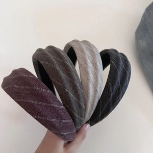 Detail of four vintage herringbone fabric headbands in red, green, grey, and black colors
