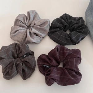 Detail of four textured fabric scrunchies in grey, black, brown and burgundy colors