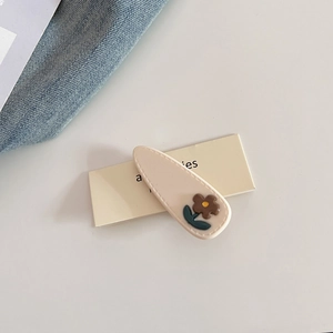 Detailed shot of cream acetate floral hair clip with stitched edges and brown flower decoration