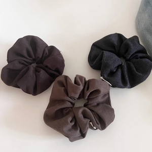 Detailed view of three wool-blend scrunchies in brown, tan and charcoal grey colors