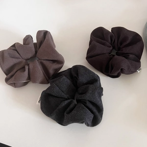 Close-up of three dark cotton scrunchies in coffee black and grey with small white labels