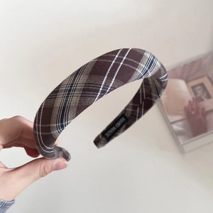 Detail of a brown plaid sponge headband with a hand made woven label on the inner side
