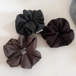 Detail showing high-quality wool fabric texture and labels on three neutral-colored scrunchies
