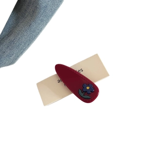 Elegant burgundy acetic acid hair clip with blue flower detail on white background