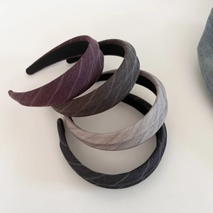 Close-up of four wide-brim striped headbands in purple, grey, and black fabric textures
