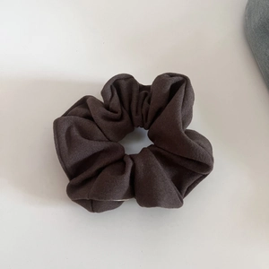 Detailed texture of dark brown wool fabric scrunchie with rich elastic folds