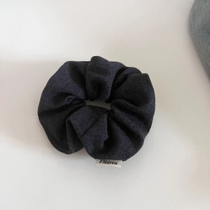 Detailed macro view of dark grey fabric scrunchie texture with a white sewn-in logo label
