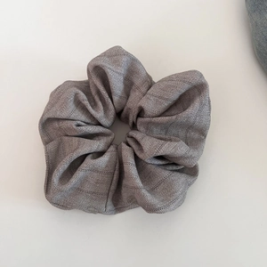 Detail of grey herringbone fabric scrunchie showing premium texture and weave patterns