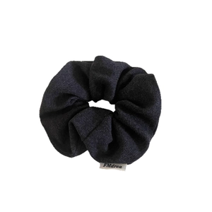 Minimalist charcoal grey wool hair scrunchie with white brand label on white background