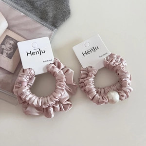 Detail of pink satin hair scrunchies with white pearls on a branded display card