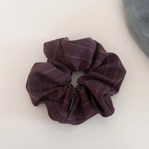 Macro view of burgundy striped fabric scrunchie with a black brand label detail