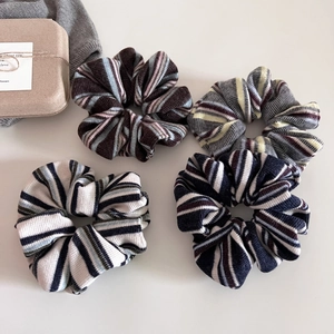 Close-up of four knitted striped scrunchies in brown, gray, white and navy blue colors