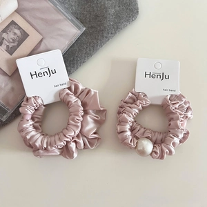 Detail of pink satin scrunchies set with white pearl ornament on premium paper card