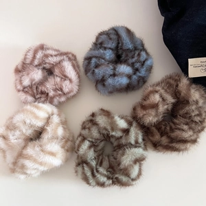 Flat lay of five plush zebra print scrunchies in assorted soft faux fur colors