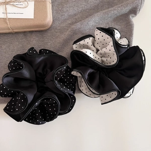 Detailed view of large black and white polka dot satin hair scrunchies with layered edges