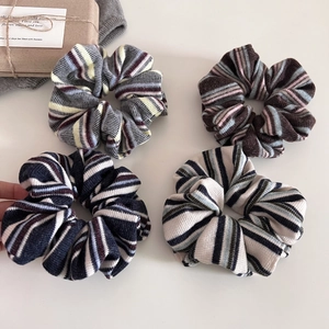 Flat lay of four colorful striped knit scrunchies with retro American college style aesthetic