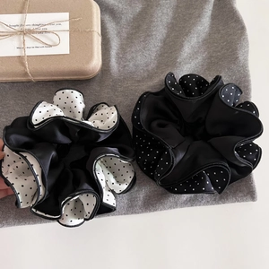 Detail of polka dot satin scrunchies with stitching on a soft fabric background
