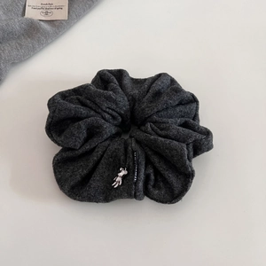 Detailed texture of grey knit scrunchie with a cute silver metal bear charm accent