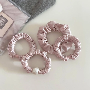 Detailed view of pink satin scrunchies set featuring smooth fabric and elegant pearl accents