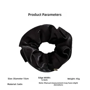 Détail d'un chouchou en satin noir de 15 cm avec une texture plissée élégante et soyeuse
