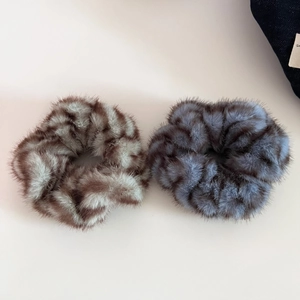 Detailed macro view of two plush faux fur scrunchies in brown and grey spotted patterns