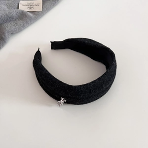 Close-up of black woolen headband with a delicate silver metal bear charm accent
