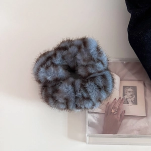 Close-up of fluffy faux fur scrunchie in misty blue and brown pattern for bun hair styling