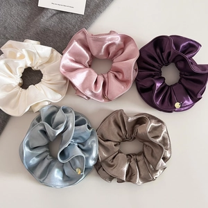 Vue rapprochée de cinq grands chouchous en satin de couleurs variées avec charme doré