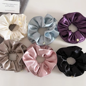 Vue à plat de six chouchous élégants en satin aux couleurs assorties avec breloques
