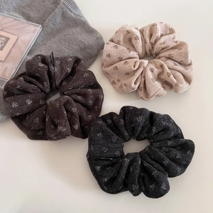 Three knit floral scrunchies in beige, brown, and charcoal gray with winter patterns