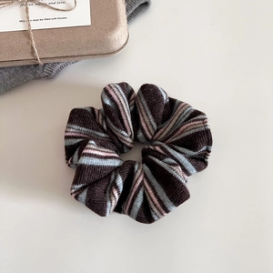 Detail of soft striped knit scrunchie in brown and blue with retro aesthetic