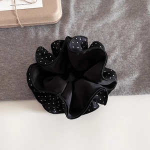 Macro shot of large black and white polka dot satin scrunchie with layered edges