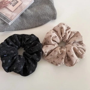 Close-up of knit floral scrunchies in beige and dark grey with delicate petal patterns