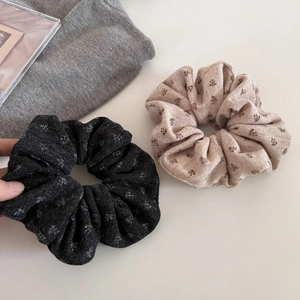 Detailed view of floral knit scrunchies in black and beige displayed on a sweater