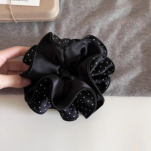 Close-up of four-layer black and white polka dot satin scrunchie with detailed stitching