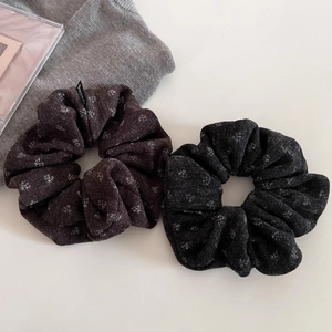 Detail of dark brown and charcoal grey knit scrunchies with fine textures and woven labels