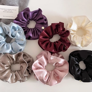Vue détaillée du lot de 7 chouchous en satin avec texture lisse et breloques en métal doré