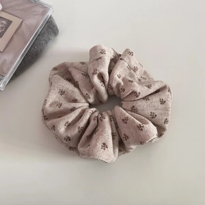 Close-up of beige knitted floral scrunchie with detailed vintage pattern texture