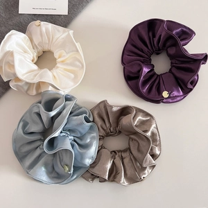 Gros plan détaillé de quatre chouchous en satin bicolores avec texture brillante et étiquettes