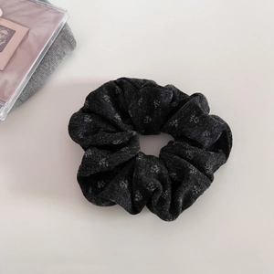 Detailed view of dark grey knitted scrunchie with silver snowflake patterns and soft texture