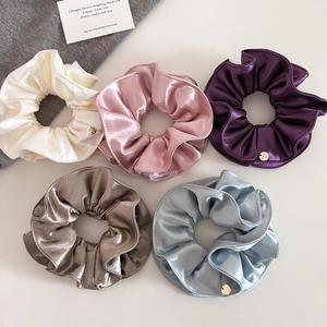 Vue à plat de cinq chouchous élégants en satin plissé aux tons pastel avec breloques