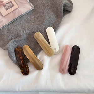 Set of six retro acetate spring hair clips in tortoiseshell and amber tones on white linen
