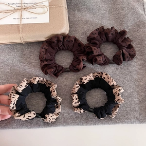 Set of 4 leopard print hair scrunchies in brown and black chiffon on a textured cloth